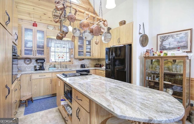 kitchen with tasteful backsplash, black appliances, a center island, light brown cabinetry, and wooden walls