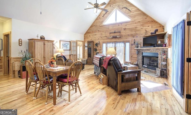 dining area with high vaulted ceiling, ceiling fan, plenty of natural light, and a stone fireplace