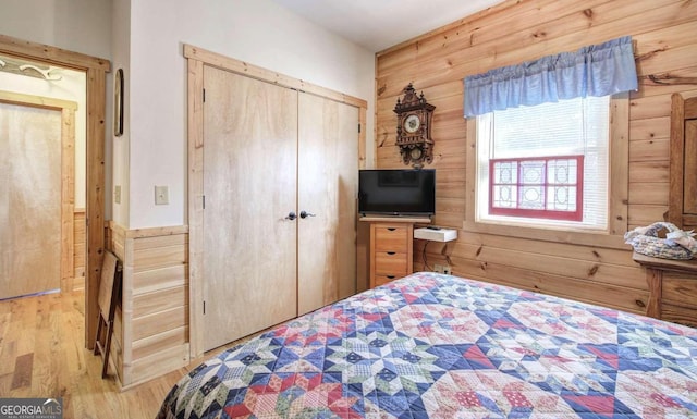 bedroom featuring a closet, light wood-type flooring, and wood walls