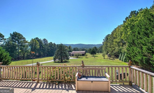 wooden terrace with a mountain view, a rural view, and a lawn