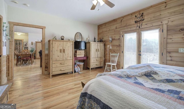 bedroom featuring light wood-type flooring, wood walls, and ceiling fan