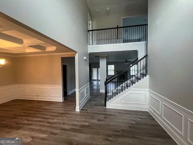 foyer with a high ceiling, ornamental molding, ceiling fan, and dark wood-type flooring