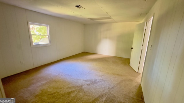 empty room with wooden walls and light carpet