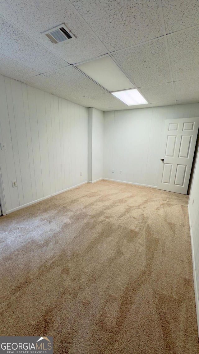 basement featuring a paneled ceiling and carpet flooring