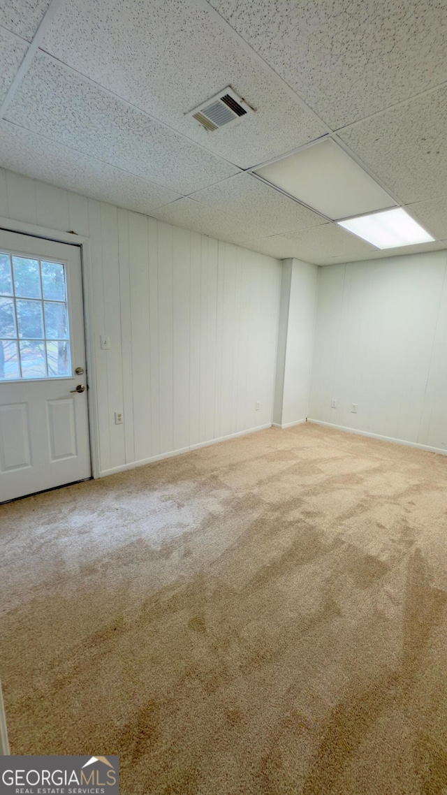 basement featuring a paneled ceiling and carpet flooring