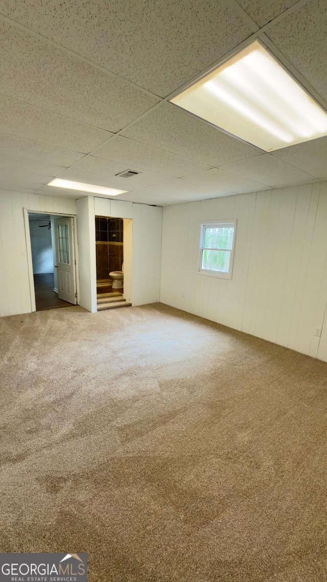 basement with carpet flooring and wooden walls