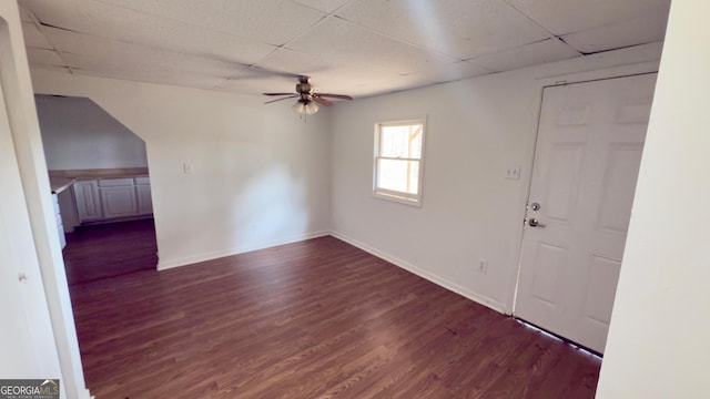 interior space with dark hardwood / wood-style flooring, a paneled ceiling, and ceiling fan