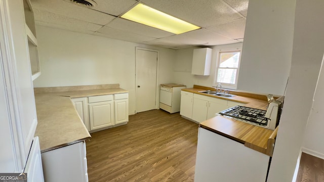 kitchen with white cabinets, sink, a drop ceiling, and light hardwood / wood-style floors