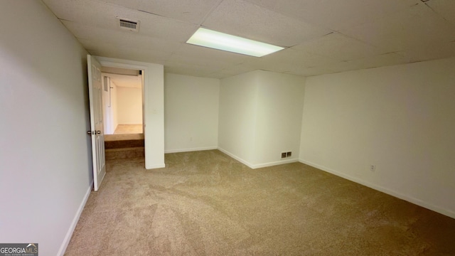 unfurnished room with light colored carpet and a drop ceiling