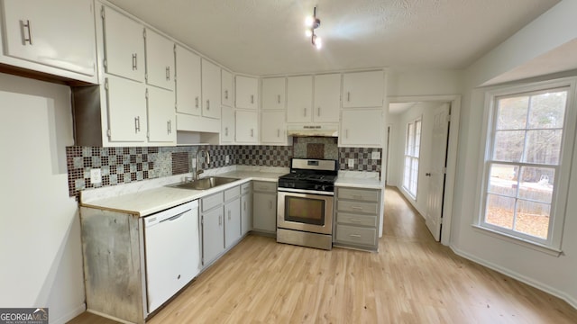 kitchen featuring sink, stainless steel gas range oven, light wood-type flooring, white dishwasher, and white cabinets