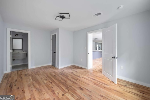 unfurnished bedroom featuring light hardwood / wood-style flooring and ensuite bath