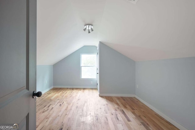 bonus room with light wood-type flooring and vaulted ceiling