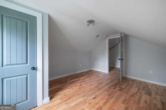 bonus room with hardwood / wood-style floors and vaulted ceiling