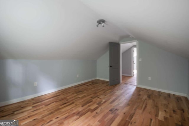 additional living space featuring wood-type flooring and lofted ceiling