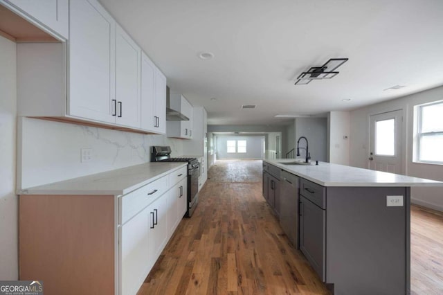 kitchen with a kitchen island with sink, sink, dark hardwood / wood-style floors, white cabinetry, and stainless steel appliances