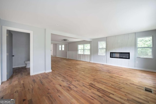 unfurnished living room featuring a fireplace, hardwood / wood-style flooring, and plenty of natural light