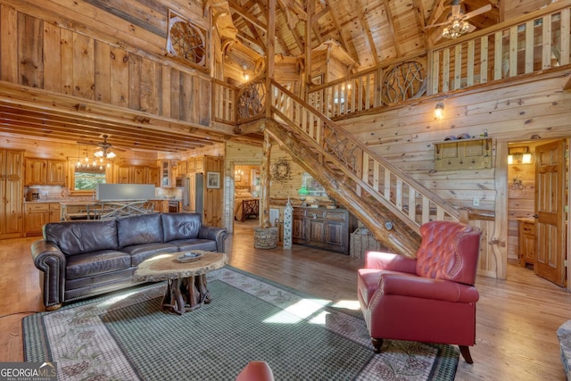 living room featuring high vaulted ceiling, light wood-type flooring, wood walls, and ceiling fan