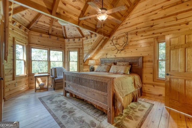 bedroom featuring light hardwood / wood-style flooring, wood walls, and multiple windows