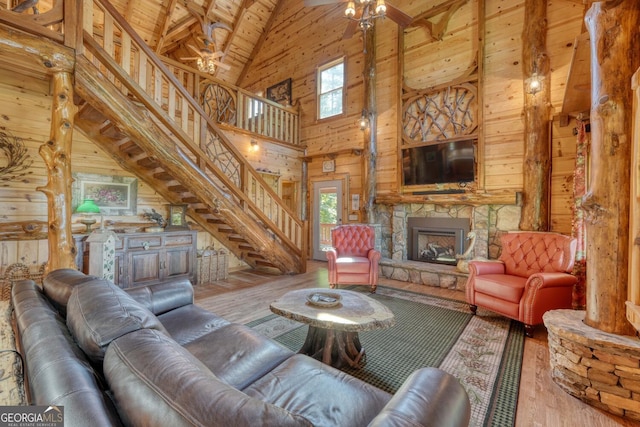 living room featuring wood ceiling, wood walls, a stone fireplace, high vaulted ceiling, and hardwood / wood-style floors