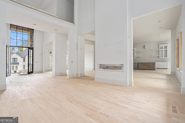 unfurnished living room featuring a high ceiling and light wood-type flooring