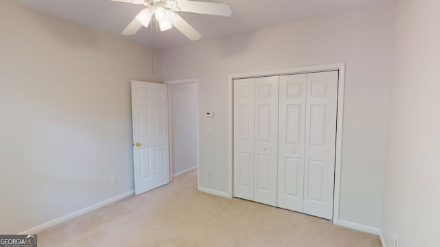 unfurnished bedroom with ceiling fan, a closet, and light carpet