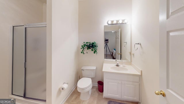 bathroom featuring tile patterned flooring, vanity, toilet, and a shower with shower door