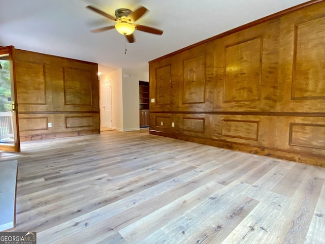 unfurnished living room featuring ceiling fan, light hardwood / wood-style flooring, and wood walls