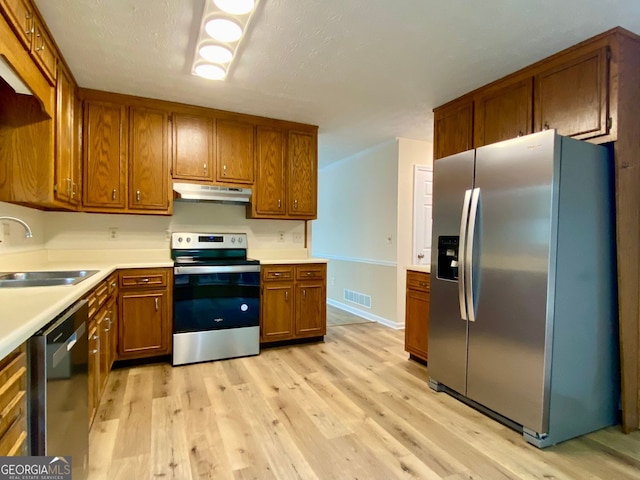 kitchen with sink, stainless steel appliances, and light hardwood / wood-style floors