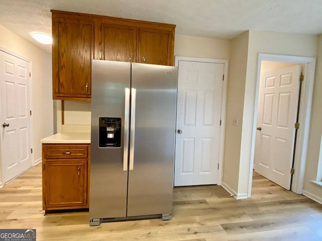 kitchen featuring stainless steel fridge with ice dispenser and light hardwood / wood-style flooring