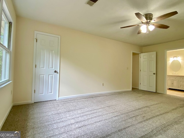 unfurnished bedroom featuring connected bathroom, ceiling fan, and light colored carpet