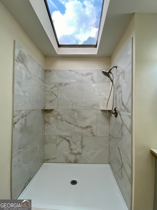 bathroom with a skylight and tiled shower