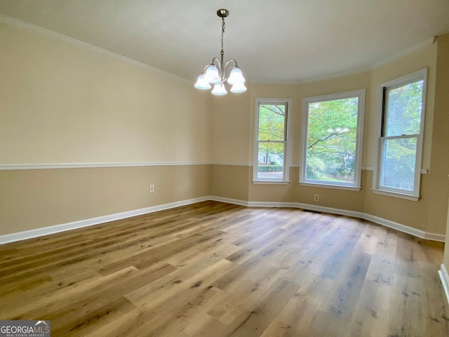 unfurnished room featuring crown molding, hardwood / wood-style floors, and a notable chandelier