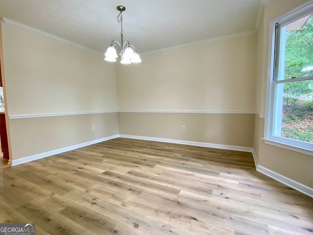 spare room with light hardwood / wood-style floors, ornamental molding, and a chandelier