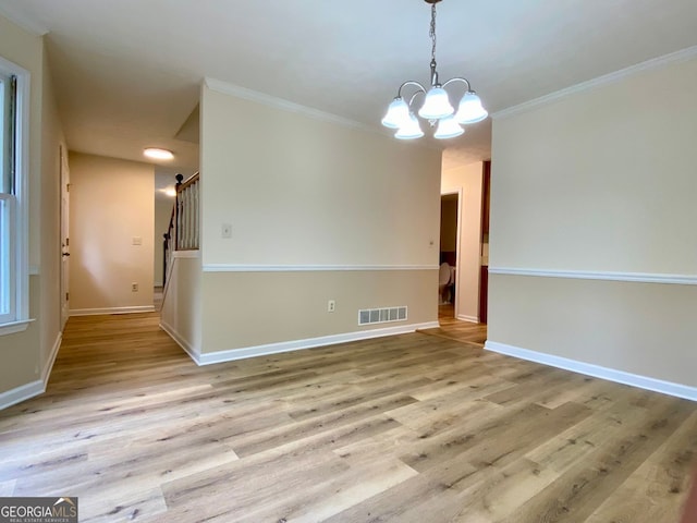 spare room with an inviting chandelier, light hardwood / wood-style flooring, and ornamental molding