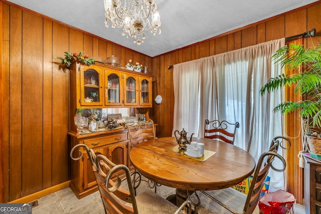 dining space featuring a notable chandelier and wood walls