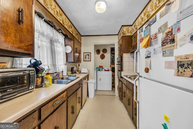 kitchen featuring sink, washing machine and clothes dryer, a textured ceiling, stainless steel appliances, and crown molding