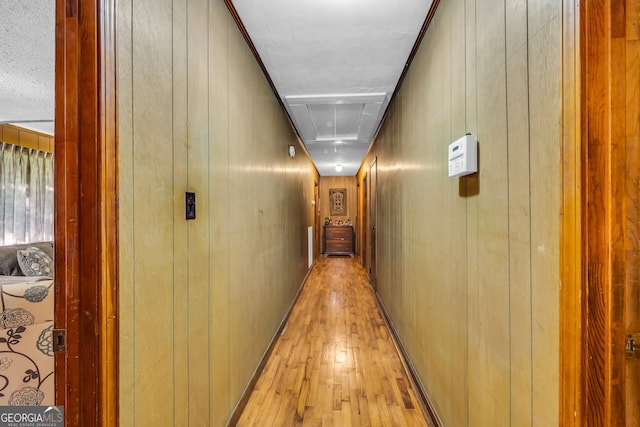 corridor with wood walls and light hardwood / wood-style floors