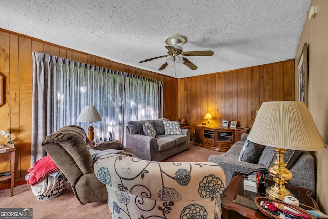 carpeted living room featuring ceiling fan, a textured ceiling, and wooden walls