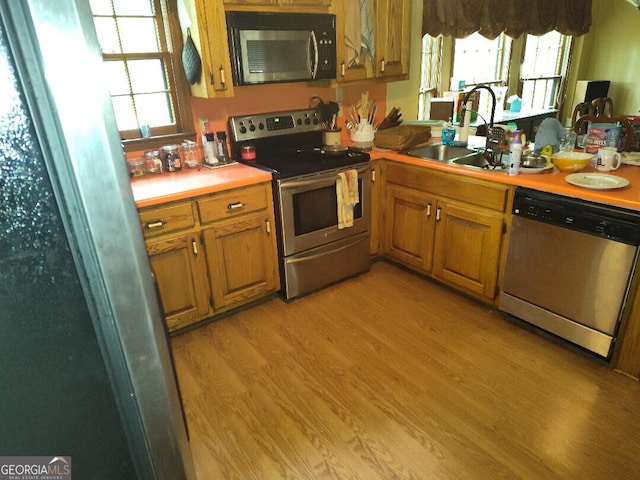 kitchen with appliances with stainless steel finishes, light hardwood / wood-style floors, and sink