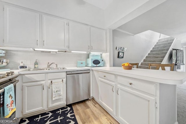 kitchen with dishwasher, white cabinets, and kitchen peninsula