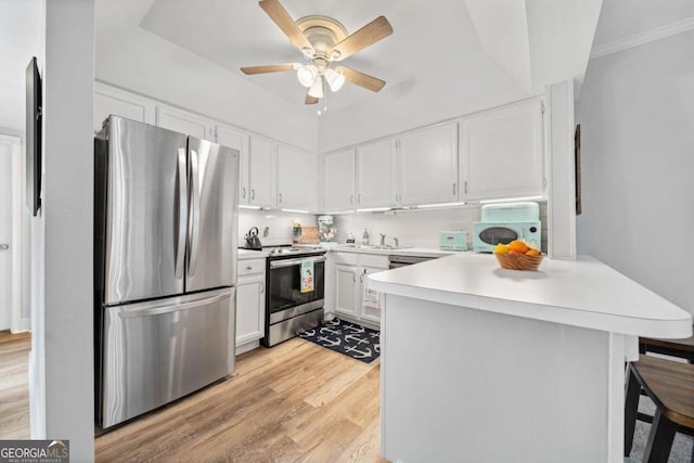 kitchen with a breakfast bar area, appliances with stainless steel finishes, white cabinetry, light wood-type flooring, and sink