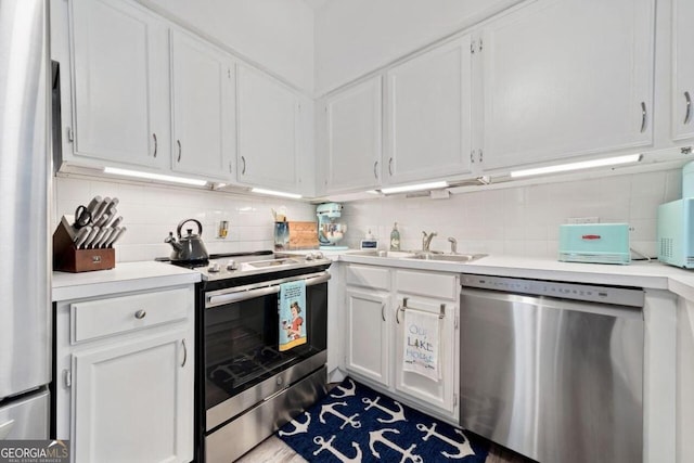 kitchen with white cabinetry, stainless steel appliances, decorative backsplash, and sink