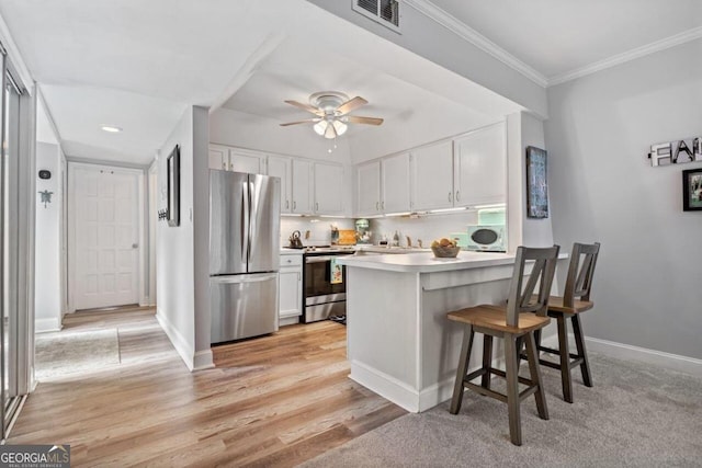 kitchen with light wood-type flooring, kitchen peninsula, stainless steel appliances, white cabinets, and a breakfast bar