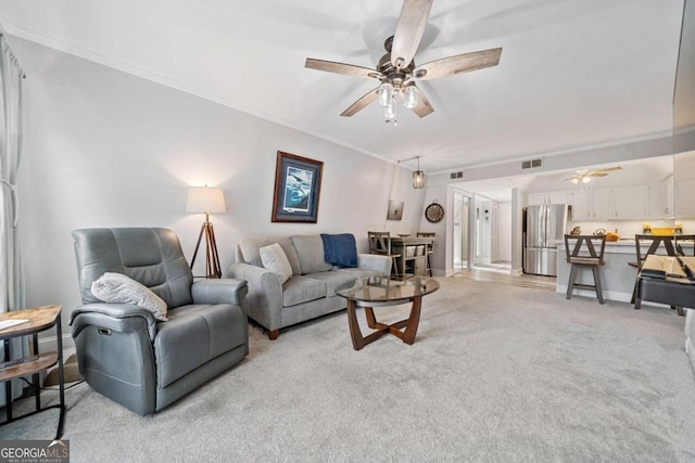 living room featuring ornamental molding, light carpet, and ceiling fan