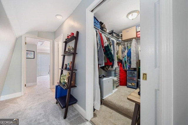 walk in closet featuring light carpet and lofted ceiling