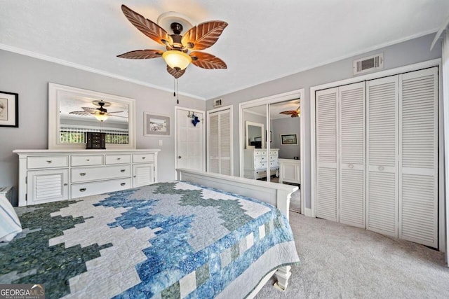 carpeted bedroom with ornamental molding, two closets, and ceiling fan