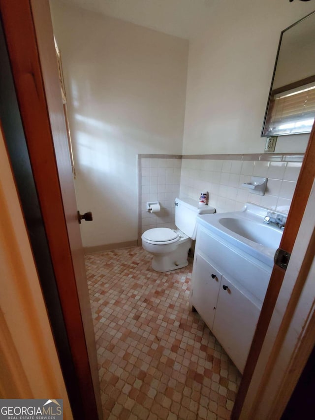 bathroom featuring vanity, tile walls, and toilet