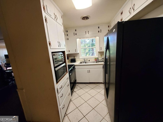 kitchen with black appliances, light tile patterned floors, and white cabinets