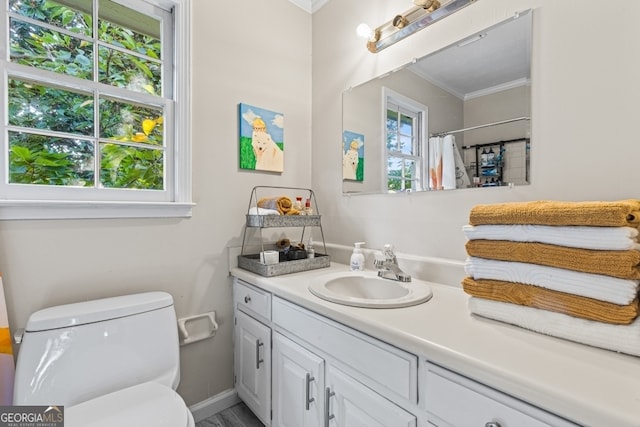 bathroom featuring ornamental molding, vanity, toilet, and a wealth of natural light