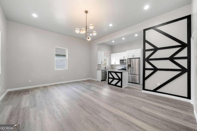 unfurnished living room with light hardwood / wood-style flooring, a chandelier, and sink